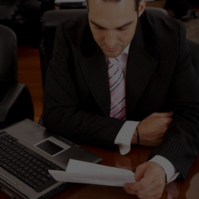 A businessman reviews documents at a desk with a laptop, demonstrating the importance of vet training compliance.