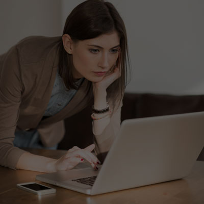 A woman types on a laptop with a concerned expression while working from home, reflecting the challenges of vet training.