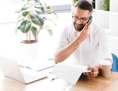 A smiling businessman talks on the phone while reviewing documents, illustrating professional development in vet training.