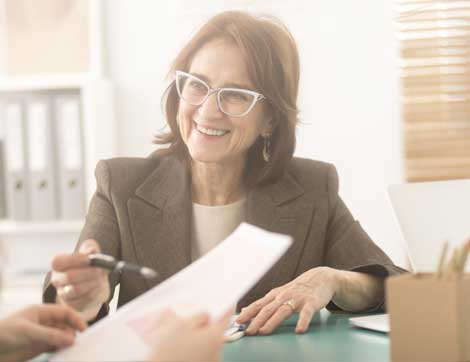 A smiling businesswoman reviews documents with a client, demonstrating professional vet training support.