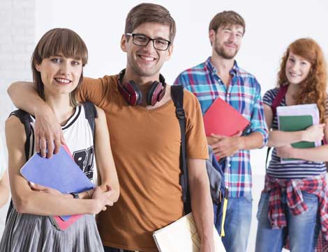 Four students pose together, holding books and smiling, demonstrating student-centred learning.